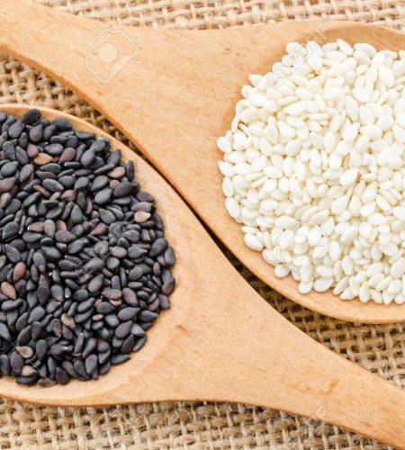 White sesame and black sesame seeds on wooden spoon.